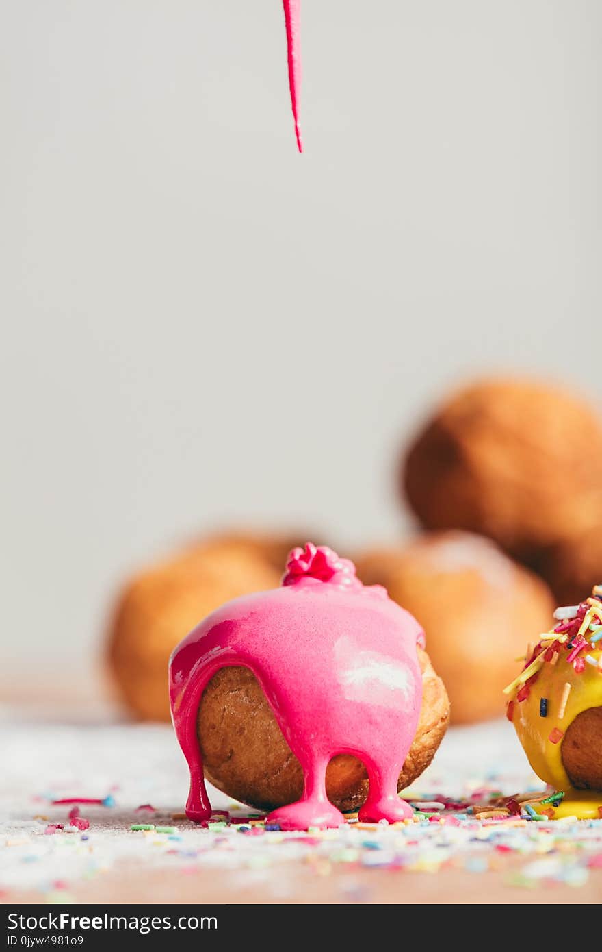 Pink liquid glaze pouring onto a homemade brown doughnut. Decorating bakings. Pink liquid glaze pouring onto a homemade brown doughnut. Decorating bakings.