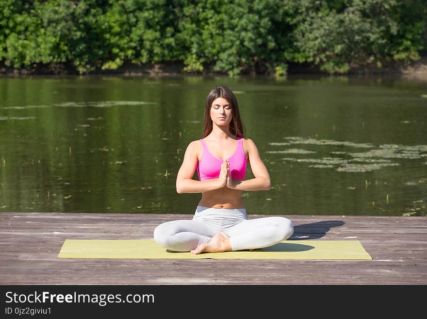 Young girl practices yoga on the shore of the lake, the concept of enjoying privacy and concentration, sunlight