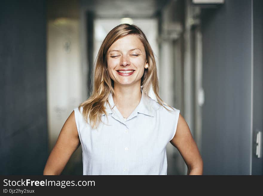 Blonde authentic and confident businesswoman with closed eyes in office hallway. Blonde authentic and confident businesswoman with closed eyes in office hallway