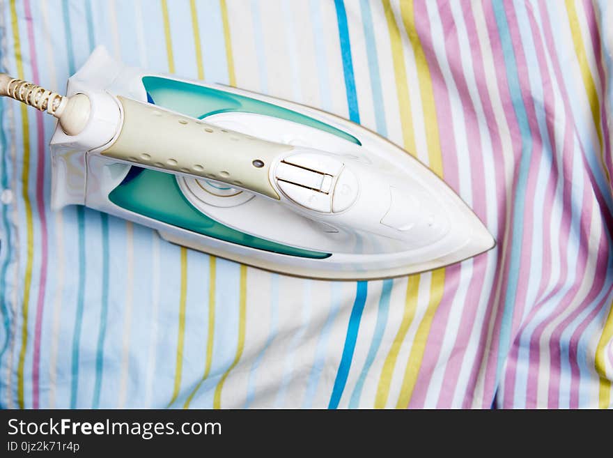 Photo of iron on striped sheet in house on ironing board