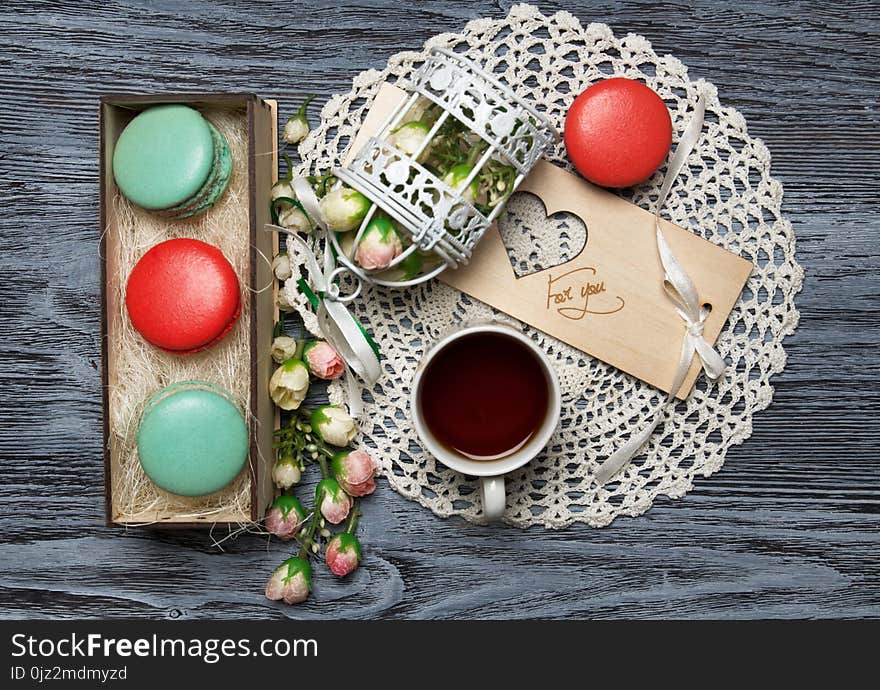 Macaroons in the box with decorations and a cup of tea