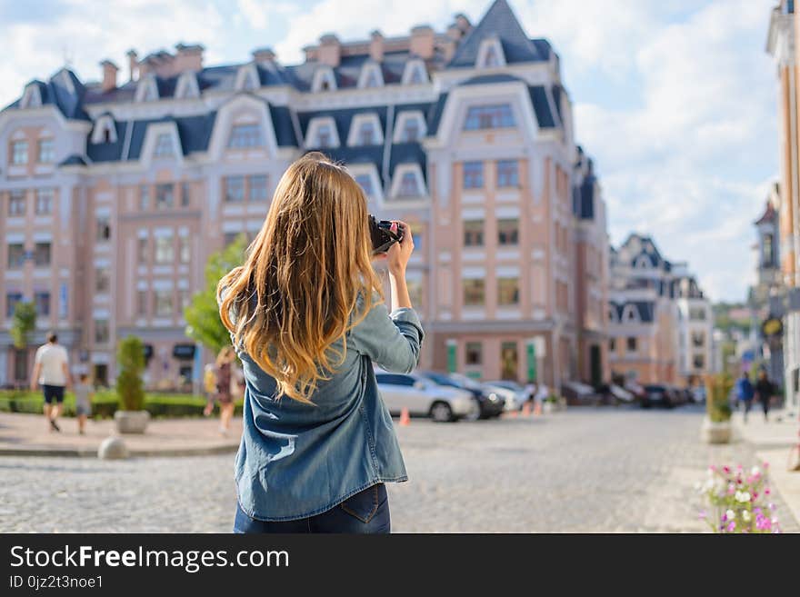 Happy, excited, stylish young woman taking photo of landmark in new old beautiful euripean city rear back behind close up view photo