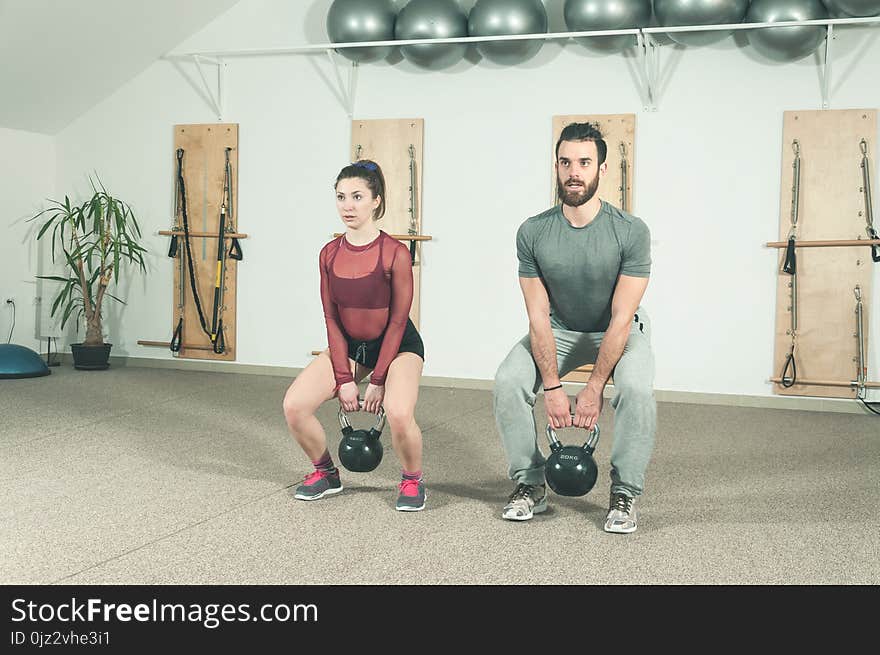 Young couple workout kettlebell fitness exercise in the gym, selective focus.