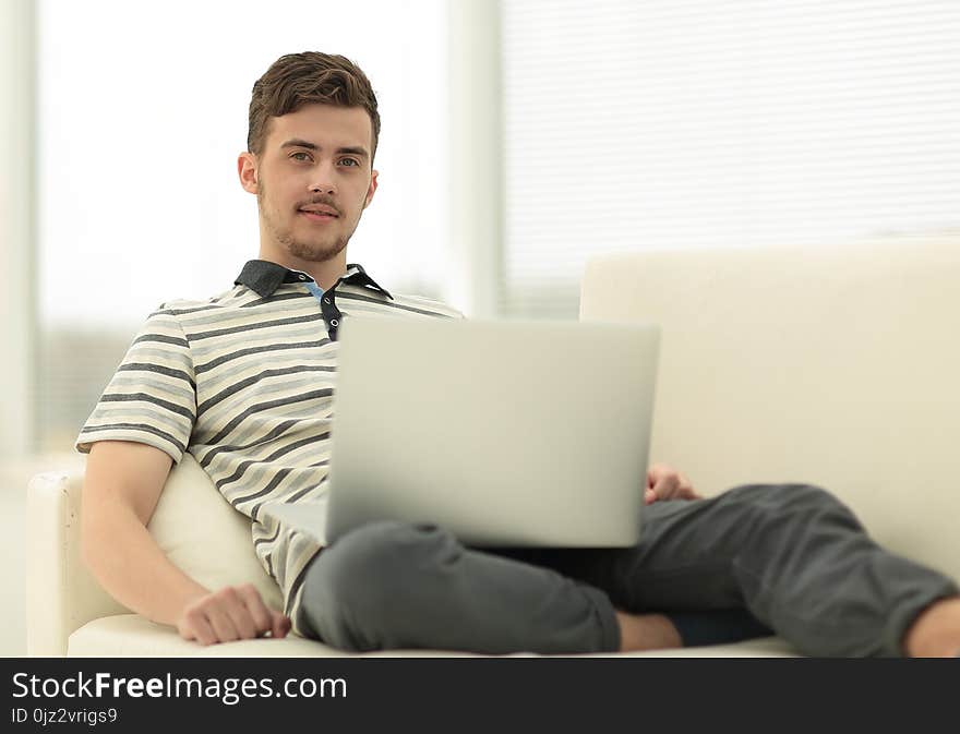 Happy man with laptop sitting on the couch. photo with copy space.