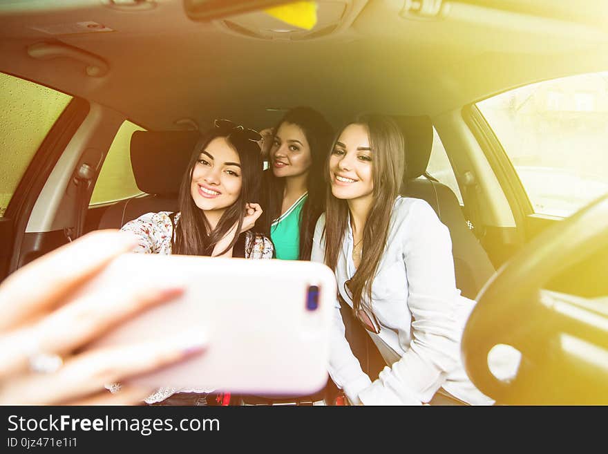 Capturing fun. Top view of three beautiful young women enjoying road trip in convertible and making selfie. Capturing fun. Top view of three beautiful young women enjoying road trip in convertible and making selfie