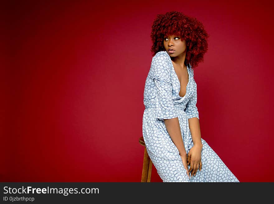 Woman Sitting on Barstool With Red Background