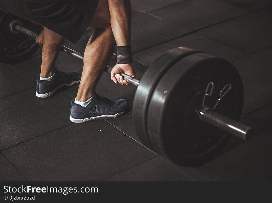 Man in Black Reebok Shoes About to Carry Barbell