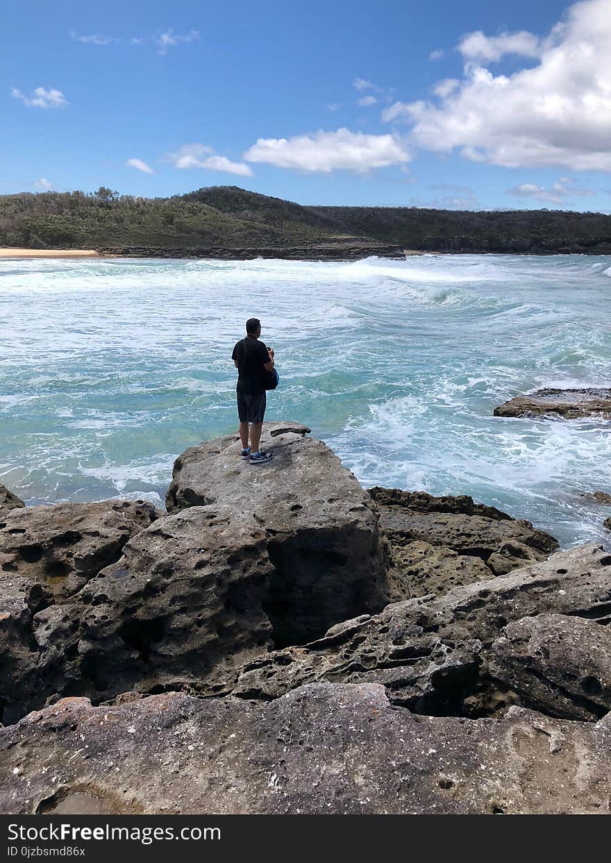 Photograph of Person on Cliff Facing Island at a Distant