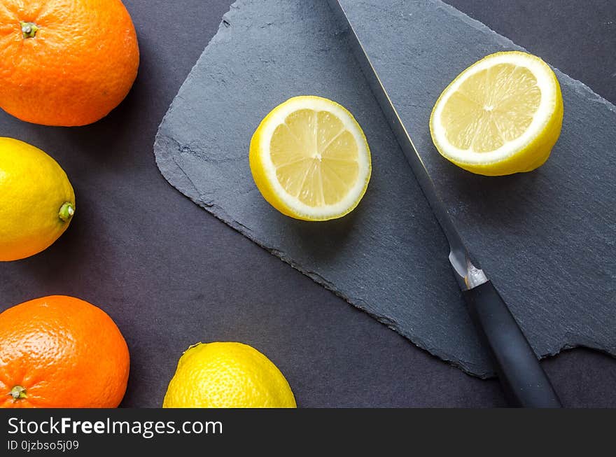 Two Orange and Three Lemons on Gray Surface