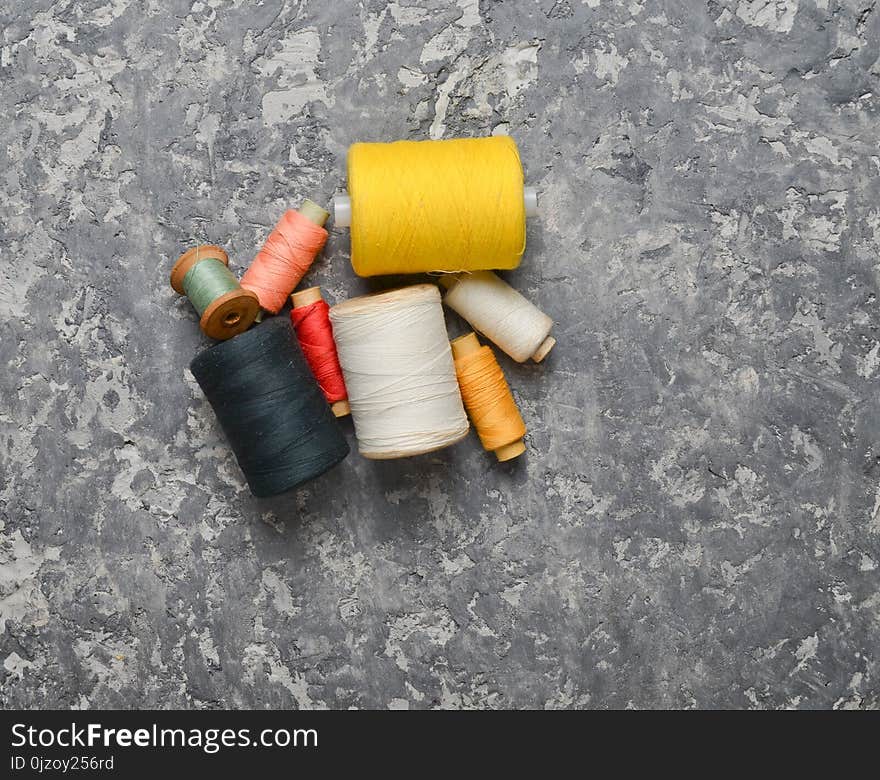 A group of multicolored skeins of thread on a gray concrete background. The concept of needlework. Made hand sewing clothes