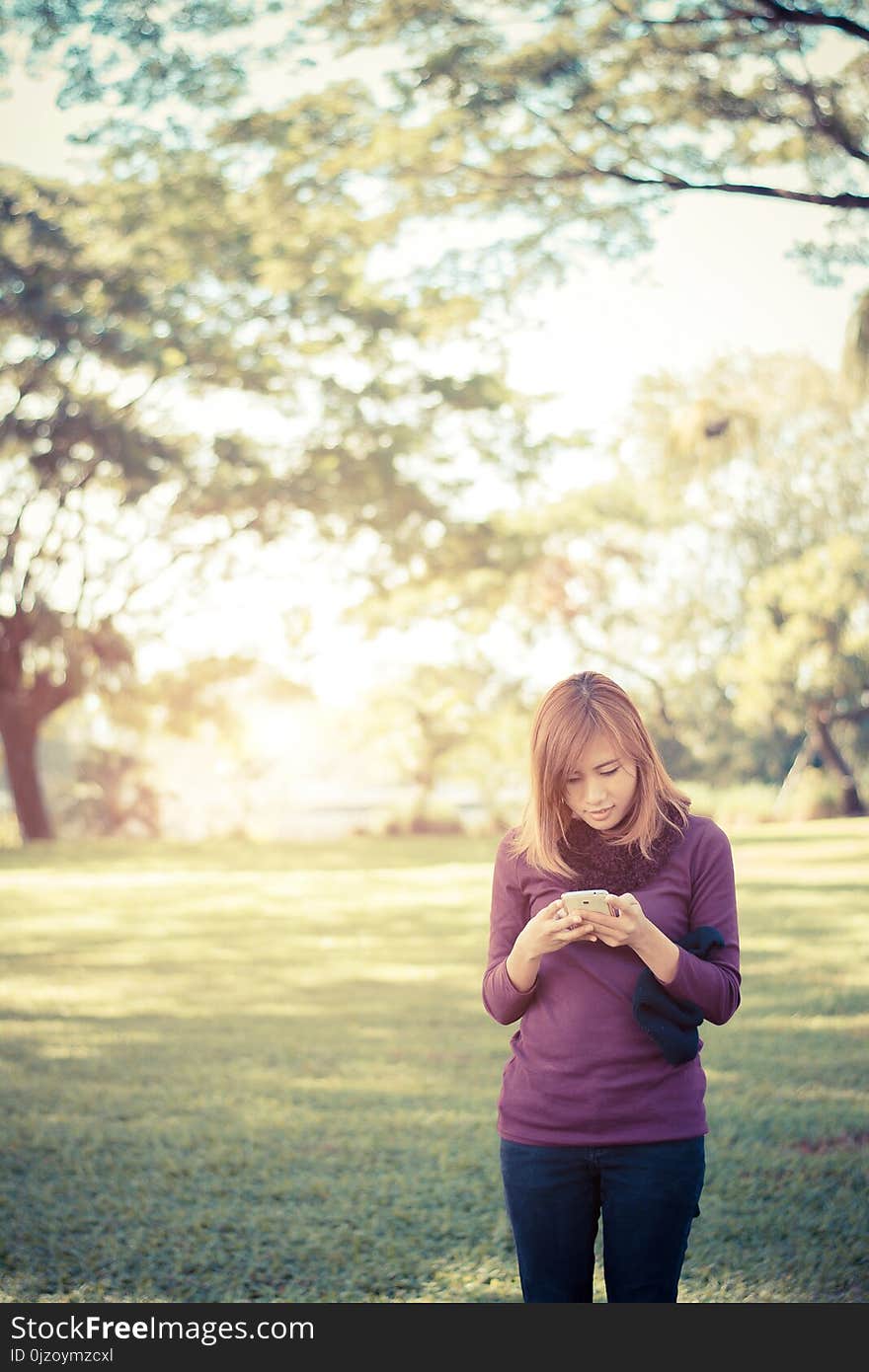 Woman standing in park writing text on smartphone At the park