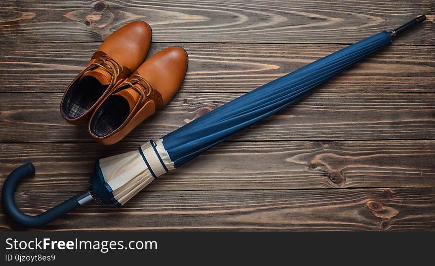 Demi-season leather half-boots and a folded umbrella on a wooden floor. Top view. Waxing women& x27;s accessories for rainy weather.