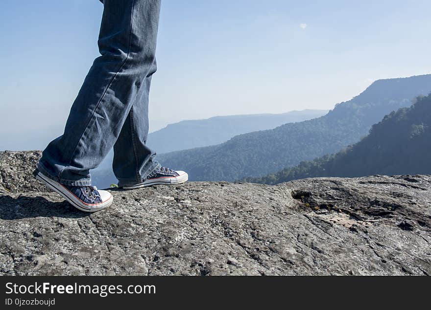 Man Walking On Edge Of A Cliff Mountain Top , Travel Concept