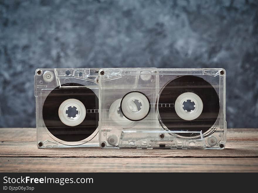 Audio Cassettes Close-up On A Wooden Shelf Against A Gray Concrete Wall. Retro Technology For Listening To Music