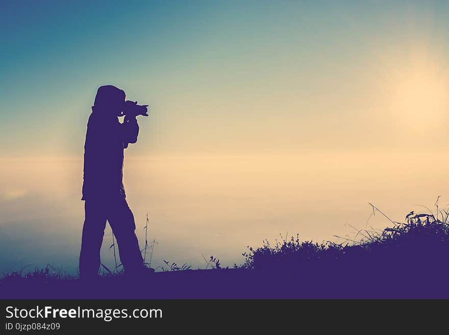 Silhouette of female photographer standing focus for take a photo and sky