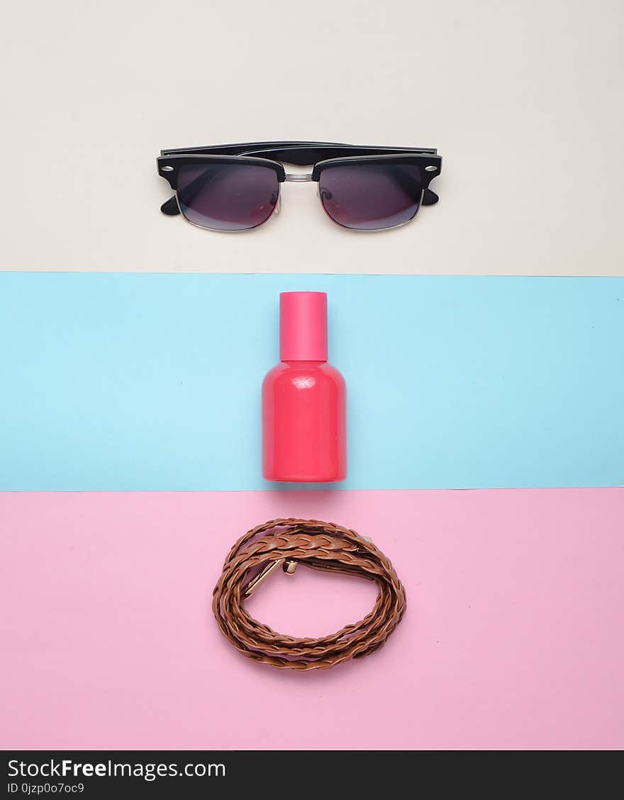 Women& x27;s trendy accessories on a multicolored pastel background. Glasses, perfume, leather belt. Top view. Minimalism