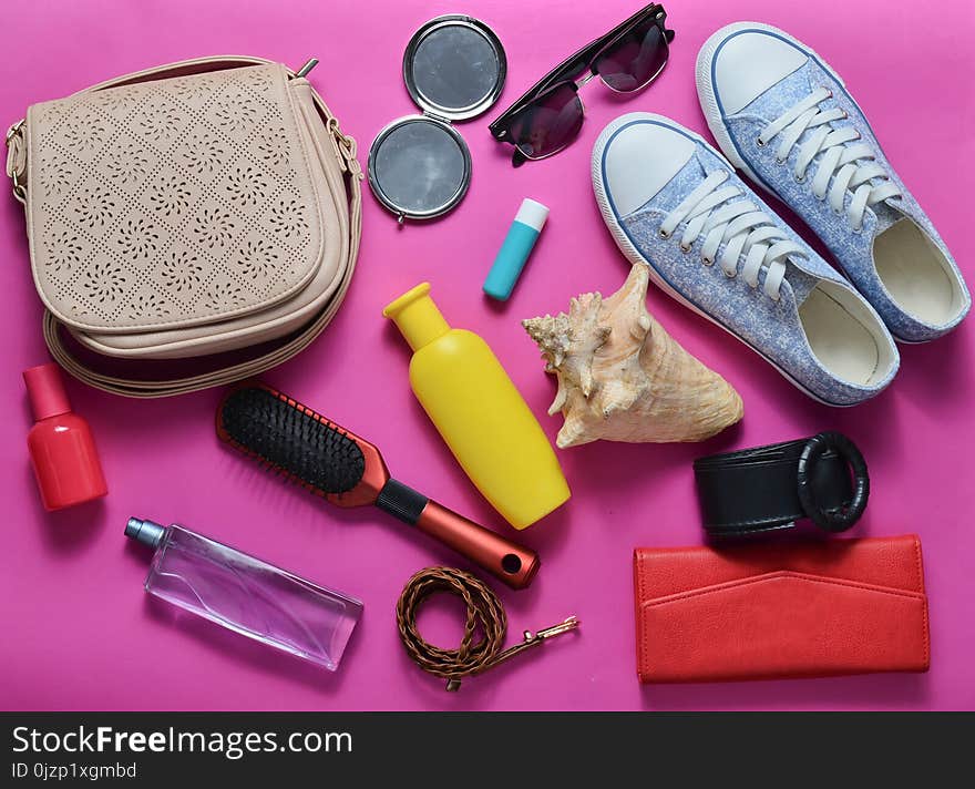 What&#x27;s in the women&#x27;s bag? Going on a trip. Girly fashionable spring and summer accessories: sneakers, cosmetics, beauty and hygiene products, a bag, sunglasses on a pink pastel background. Top view. What&#x27;s in the women&#x27;s bag? Going on a trip. Girly fashionable spring and summer accessories: sneakers, cosmetics, beauty and hygiene products, a bag, sunglasses on a pink pastel background. Top view.