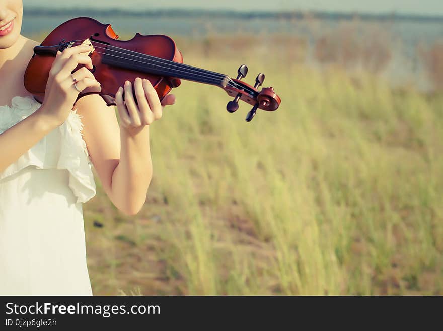 Beautiful Woman standing Playing the violin in the meadow