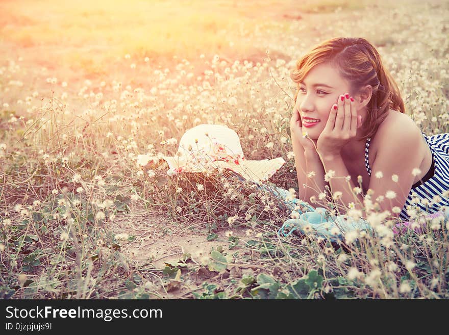 Young woman resting on the flower field and smile background