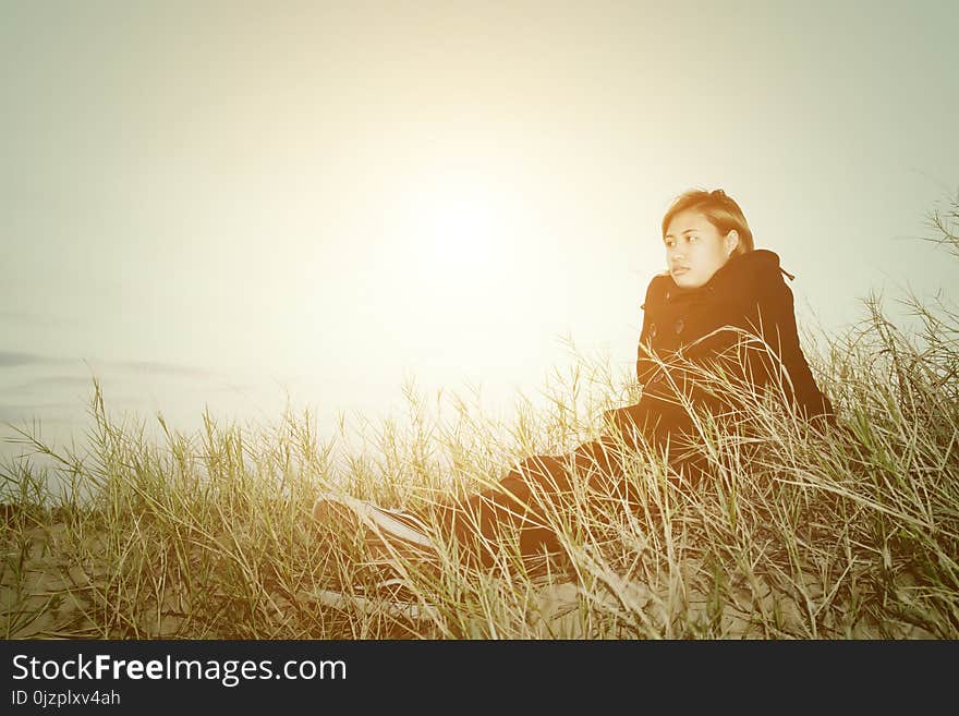 Sad young woman sitting on the grass feeling so sad and loneliness