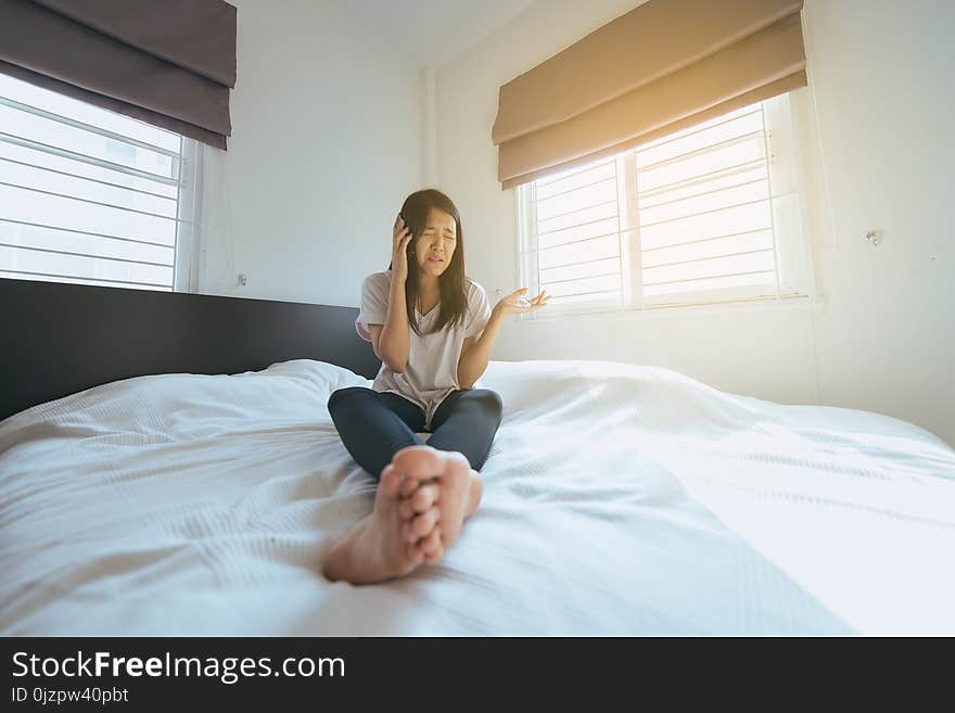 Asian woman talking with her mobilephone in bedroom at home feeling serious