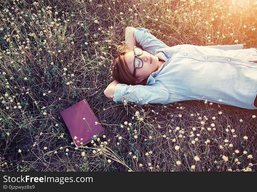 Beautiful young hipster laying down on the meadows field smiley background