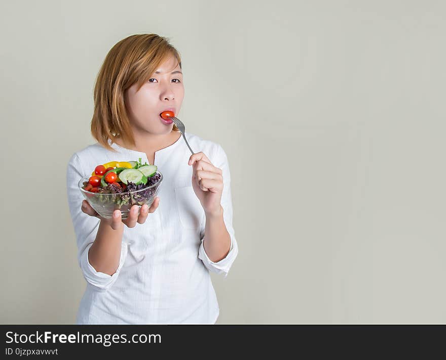 Beautiful Young Woman Using Fork To Eat A Tomato In Bowl Of Salad With Gusto.