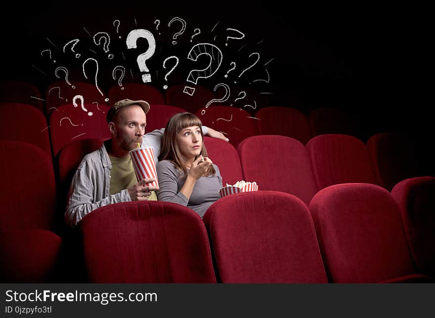 Nice couple in cinema with drawn question signs around. Nice couple in cinema with drawn question signs around