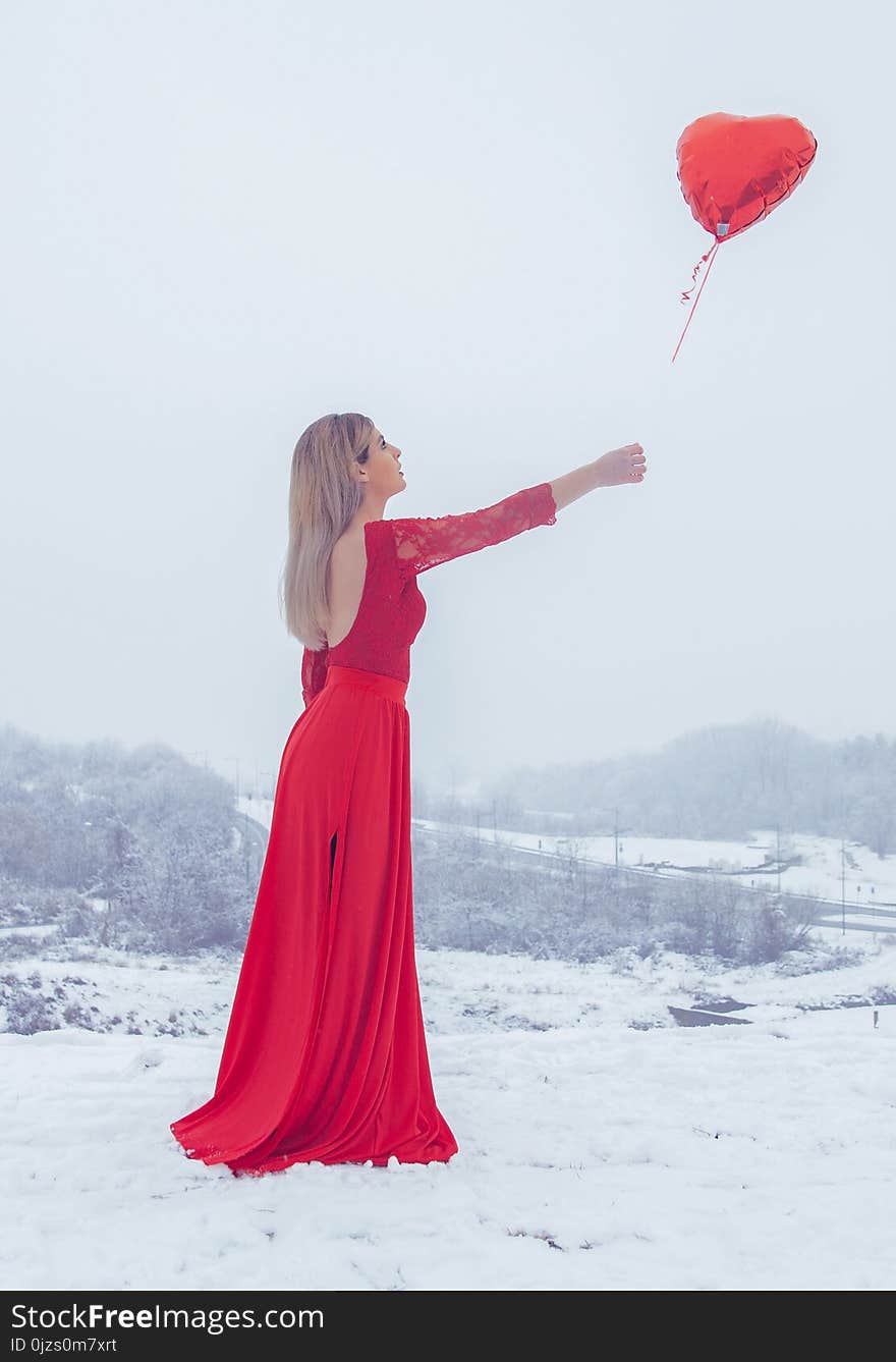 Woman in Red Floral Lace Long-sleeved Dress Standing With Red Heart Balloon