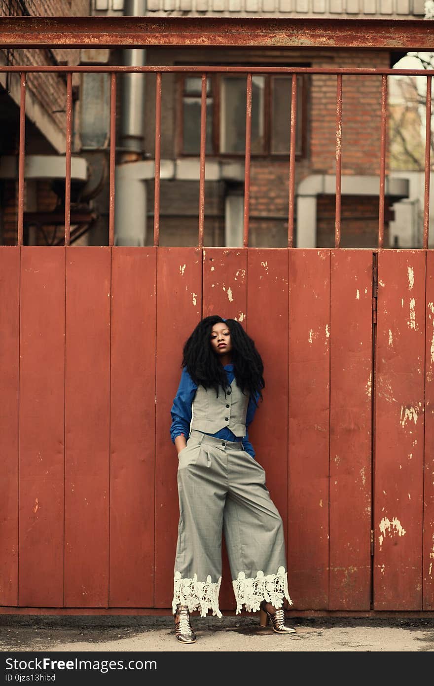 Woman Wearing Blue and Gray Outfit Standing Beside Gate