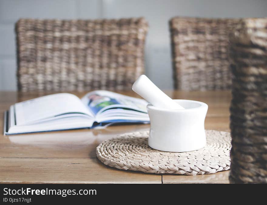 White Ceramic Mortar and Pestle Beside Book