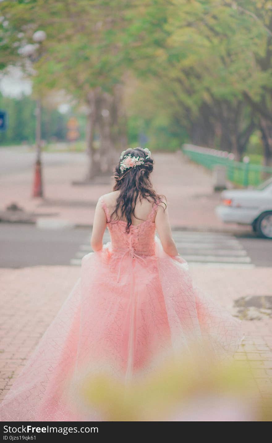 Woman Wearing Pink Floral Gown Stands Near Green Trees at Daytime