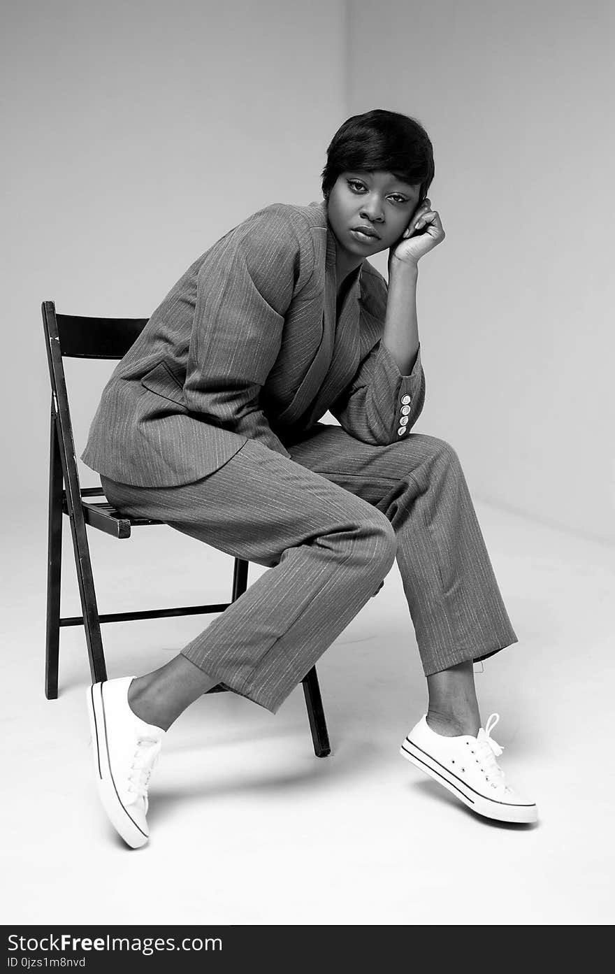 Grayscale Photo of Woman in Formal Suit Sitting on Folding Chair