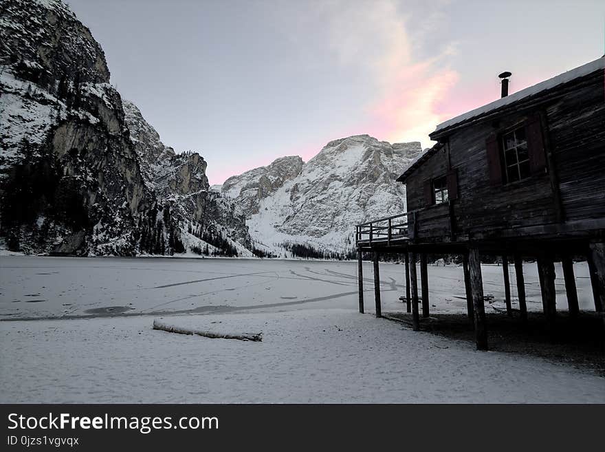 Wooden House Near Mountain Covered With Snow