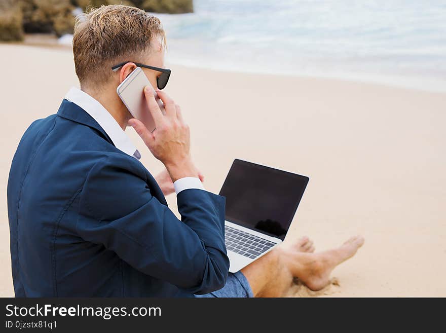 Businessman working with laptop on the beach, man is working on the beach