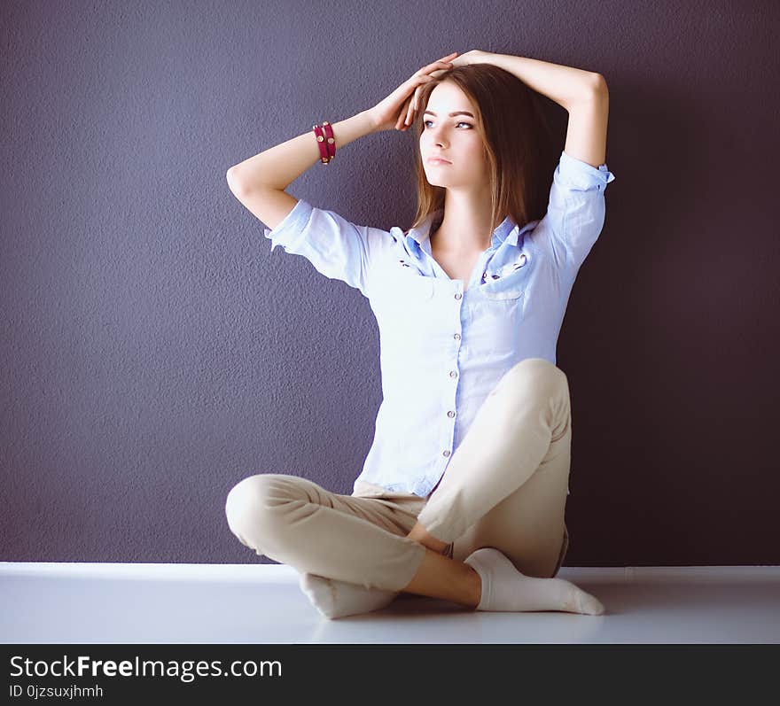 Young Woman Sitting On The Floor Near Dark Wall