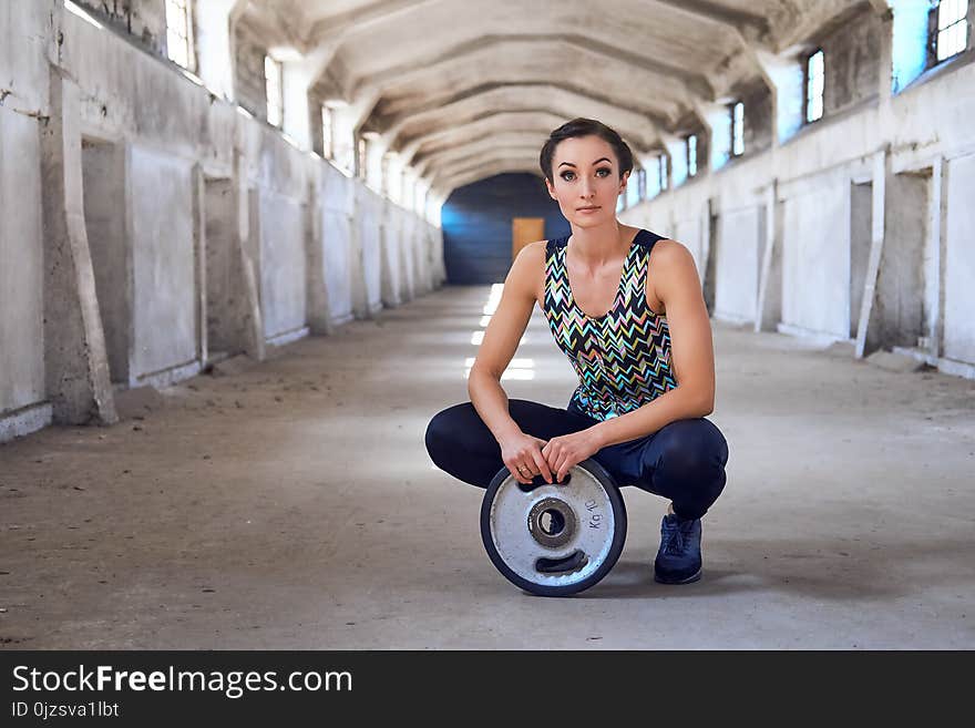 Full body portrait of the sporty female doing squats in a tunnel hull. Full body portrait of the sporty female doing squats in a tunnel hull.