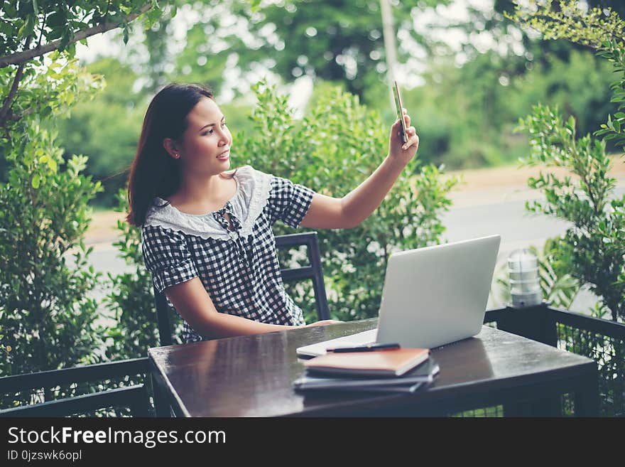 Young beautiful woman sitting at a table in a cafe, drinking coffee and doing selfie.