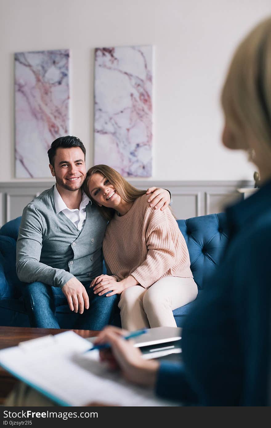 Beautiful young husband and wife are visiting a psychologist. Sitting and embracing.