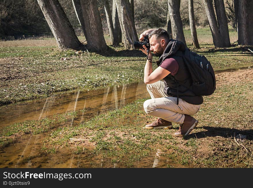 Photographer in nature takes pictures of the landscapes. Young berded man with camera.