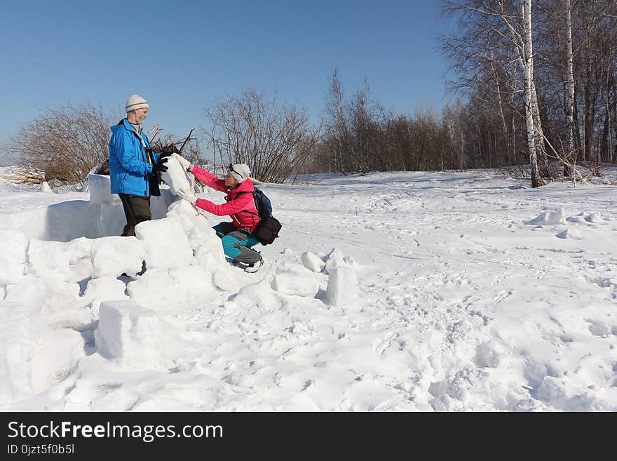 Man and woman building an igloo on a snow glade