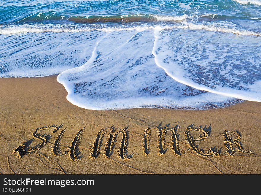 The inscription summer on sand beach on the soft sea wave background. The inscription summer on sand beach on the soft sea wave background.