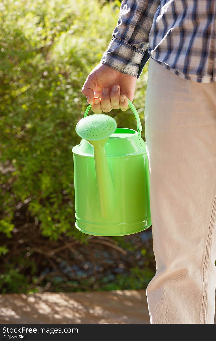 Man gardener holding watering can in garden