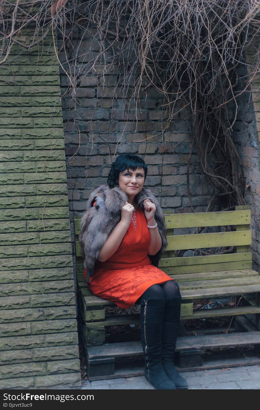 Brunette woman is sitting on a bench on an autumn day in the city. Brunette woman is sitting on a bench on an autumn day in the city