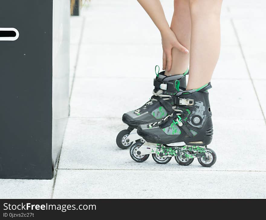 Woman slim legs wearing roller skates standing outside. Sport activity objects concept. Woman slim legs wearing roller skates standing outside. Sport activity objects concept.