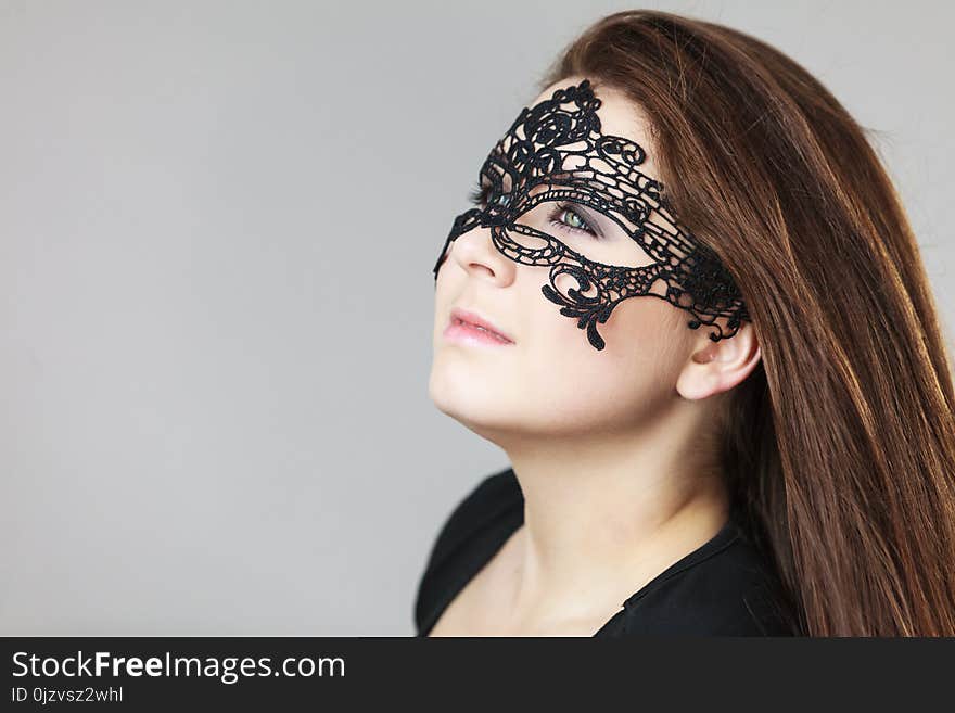 Pretty mysterious woman wearing black eye lace mask having tousled windblown long brown hair. Pretty mysterious woman wearing black eye lace mask having tousled windblown long brown hair.