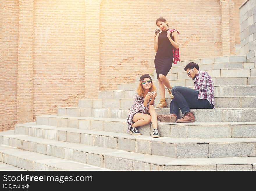 Group of hipster students sitting on a staircase talking and rel