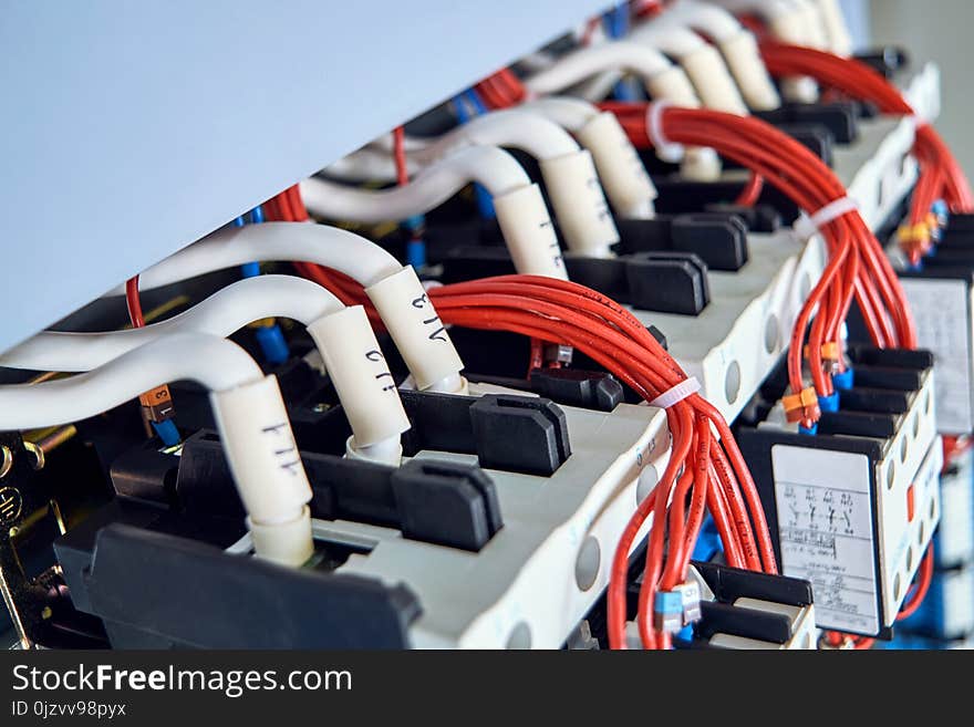 A number of magnetic starters and connected electrical wires in the electrical Cabinet. Cables with tips and digital marking. Red wires are assembled into a bundle of plastic ties. A number of magnetic starters and connected electrical wires in the electrical Cabinet. Cables with tips and digital marking. Red wires are assembled into a bundle of plastic ties.