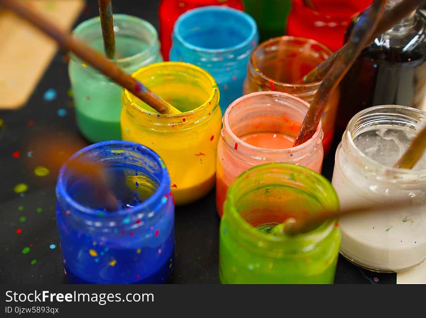 Different glass containers with different colors for painting and brushes