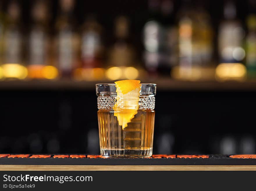 Glass of whiskey cognac or brandy with lemon and ice cubes standing on the bar counter